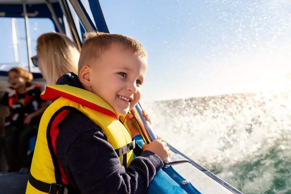 A young boy in a life vest smiling on a boat.
